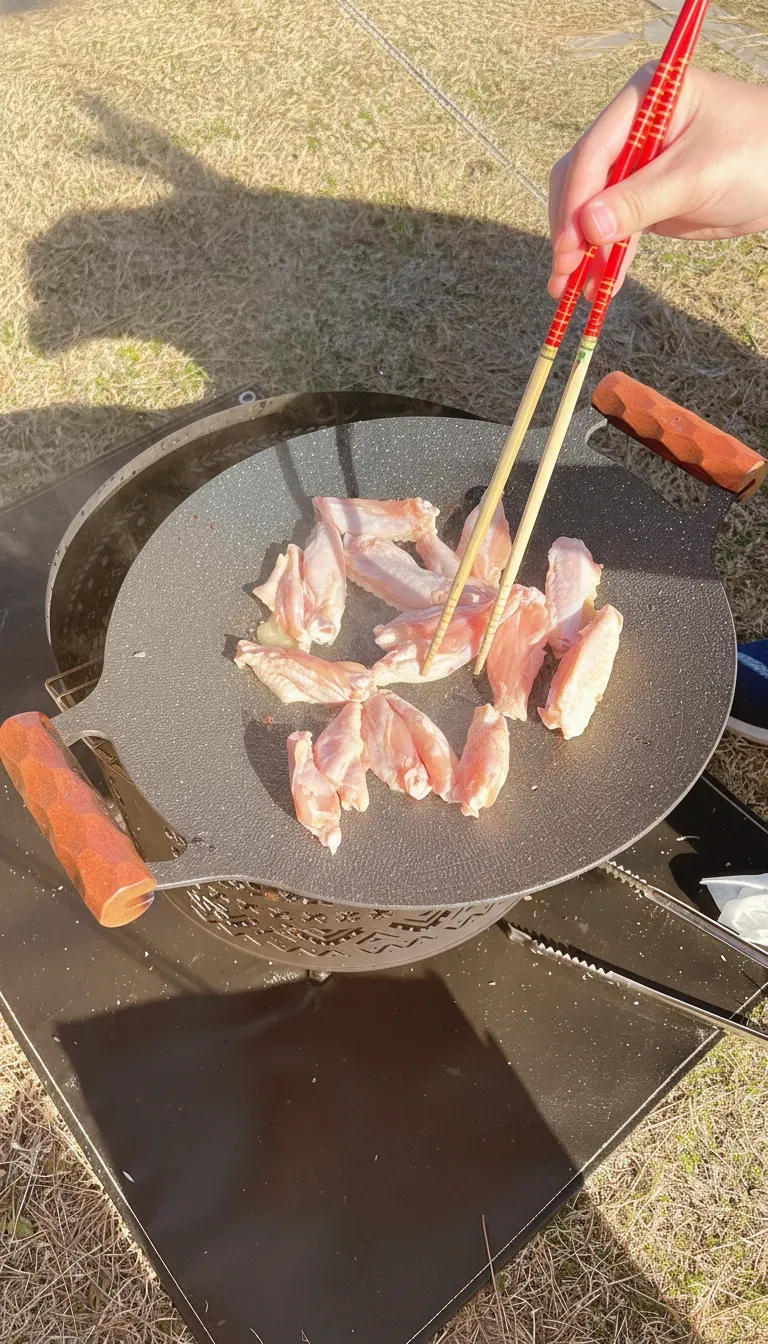 焚き火台の上のマルチグリドルで肉を焼く